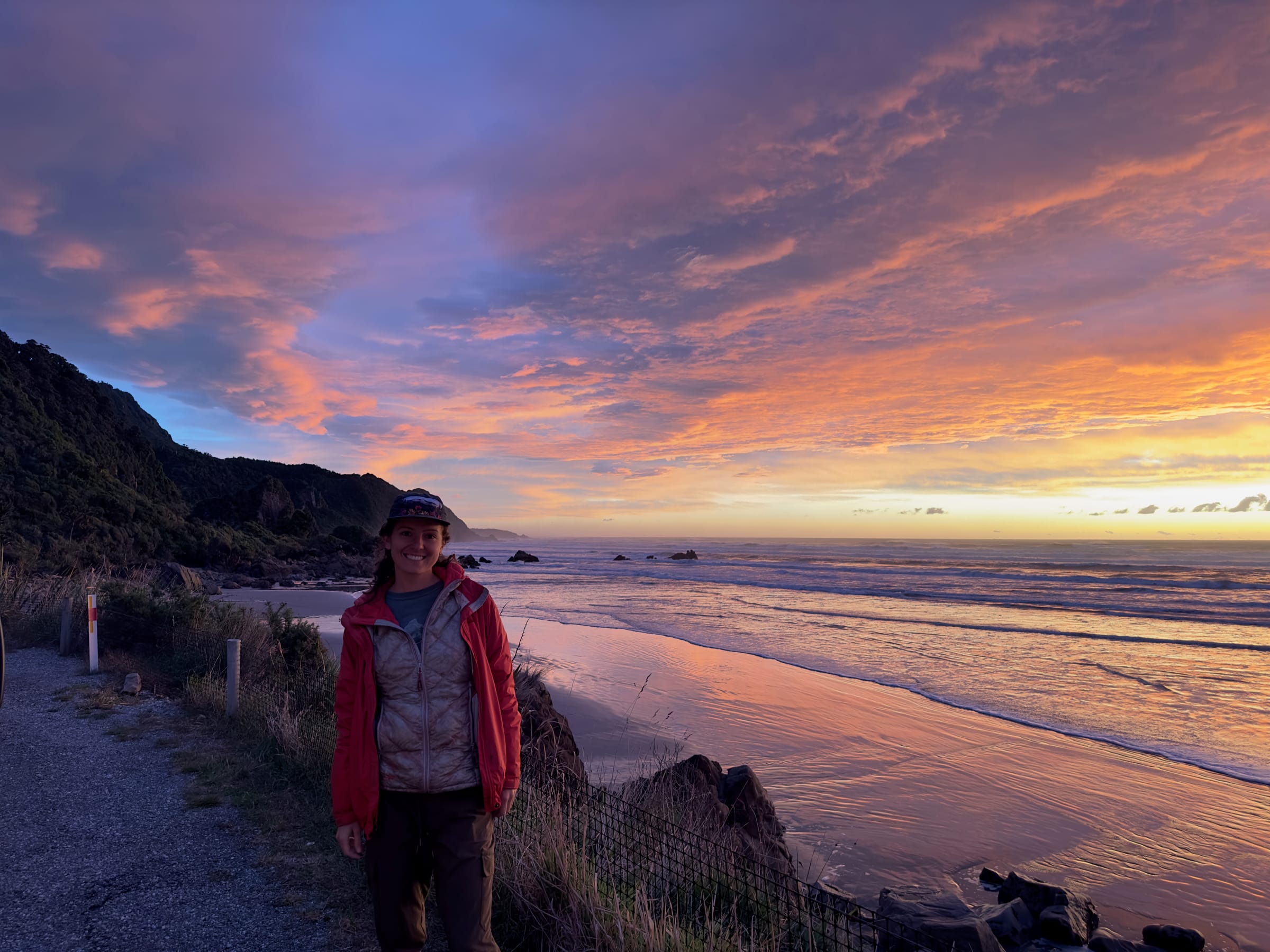 Person standing at beach during vivid sunset