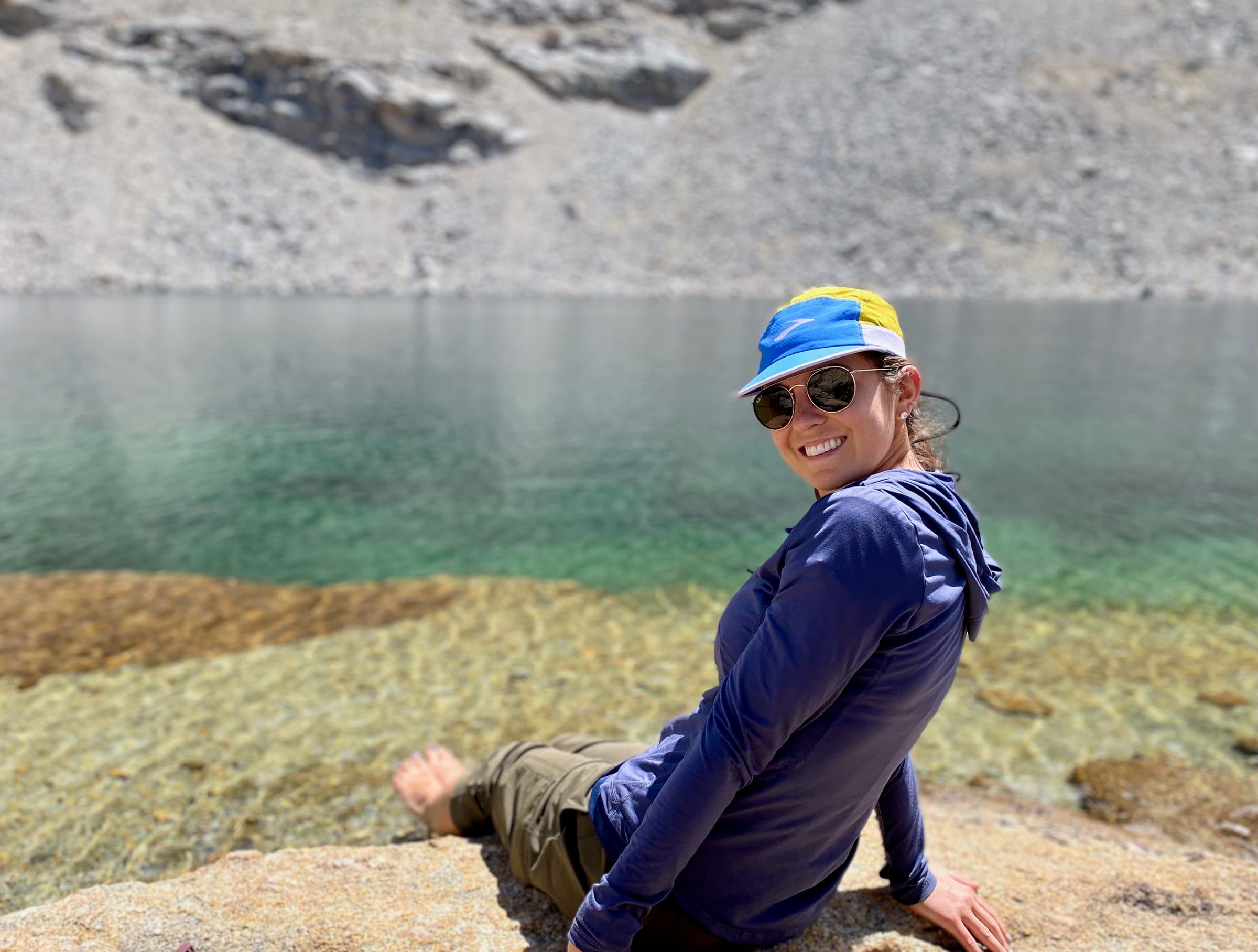 Person sitting by a clear alpine lake